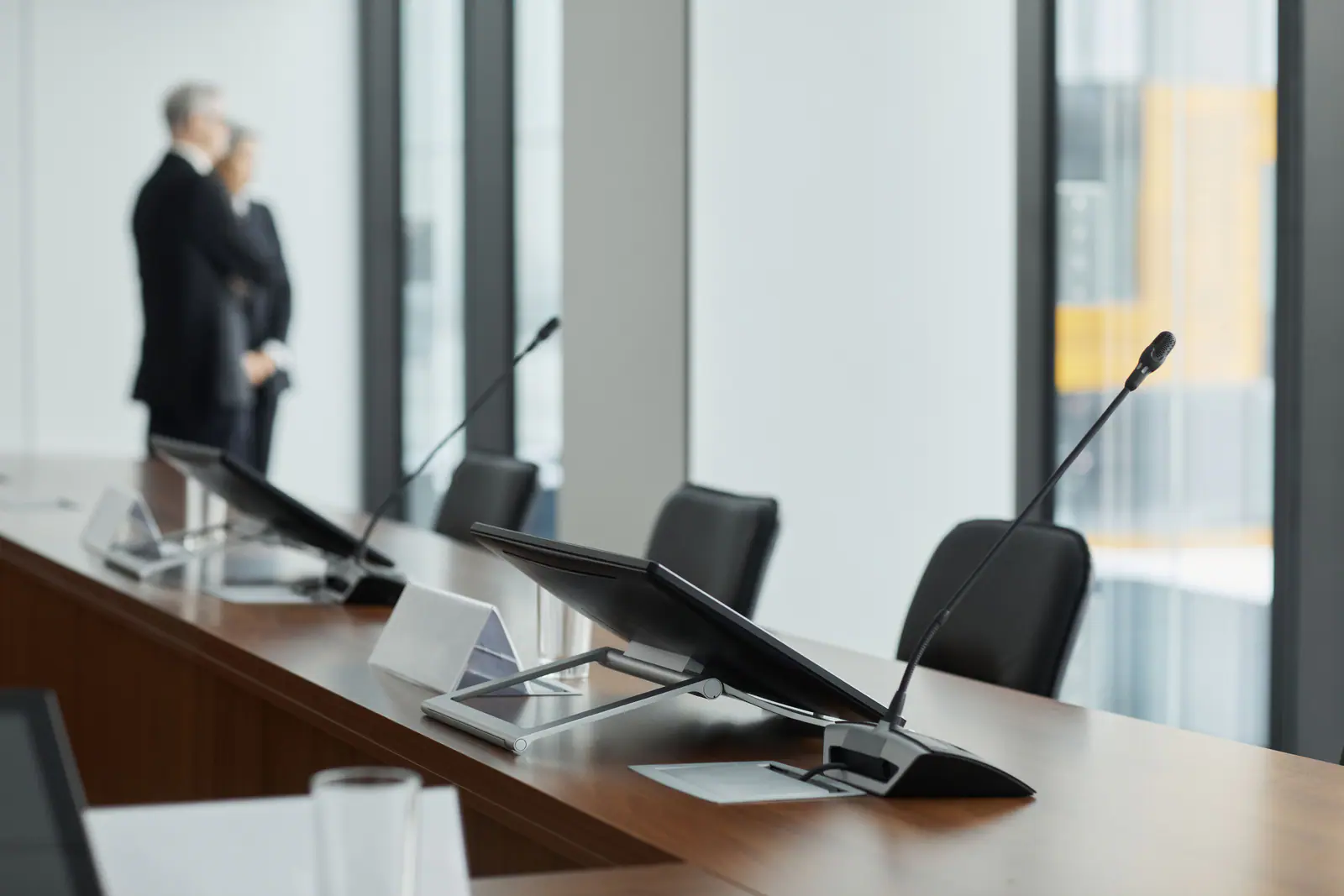 Conference room with monitors and microphones on a wooden table